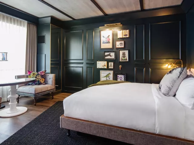 King bed rest against green wall and faces window.