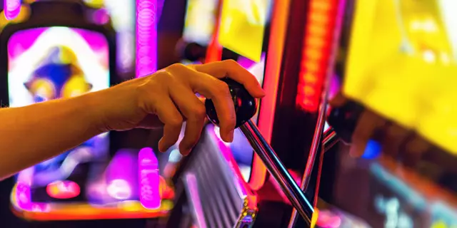 Gambling Industry Theme. Woman Playing One Handed Casino Slot Machine Game. Caucasian Hand Close Up.