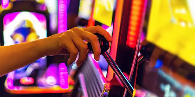 Gambling Industry Theme. Woman Playing One Handed Casino Slot Machine Game. Caucasian Hand Close Up.