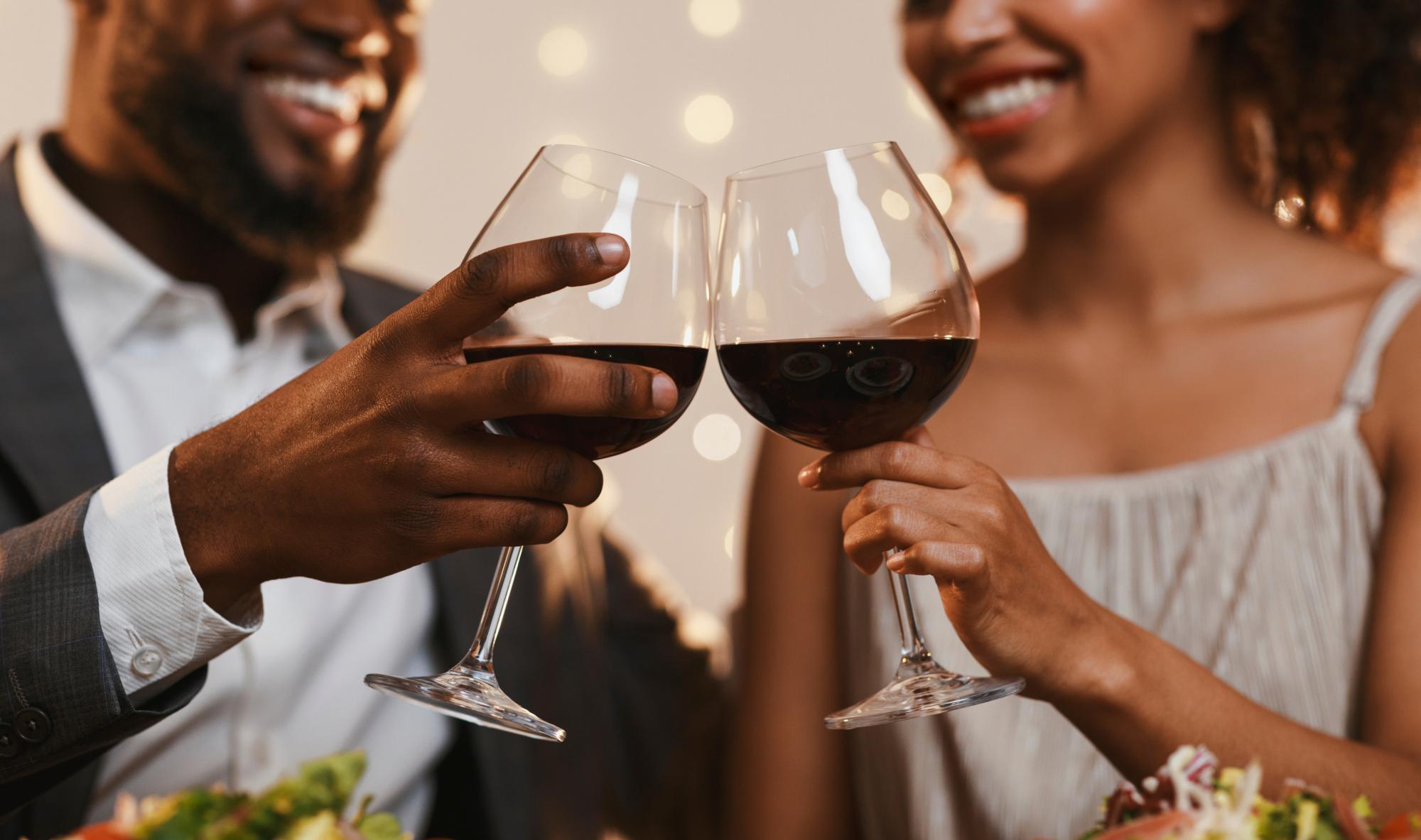 Close up of cheerful african american couple toasting with red wine, celebrating anniversary