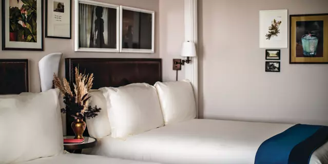Park MGM hotel bedroom with a two large beds dressed in crisp white linens and art frames on walls.