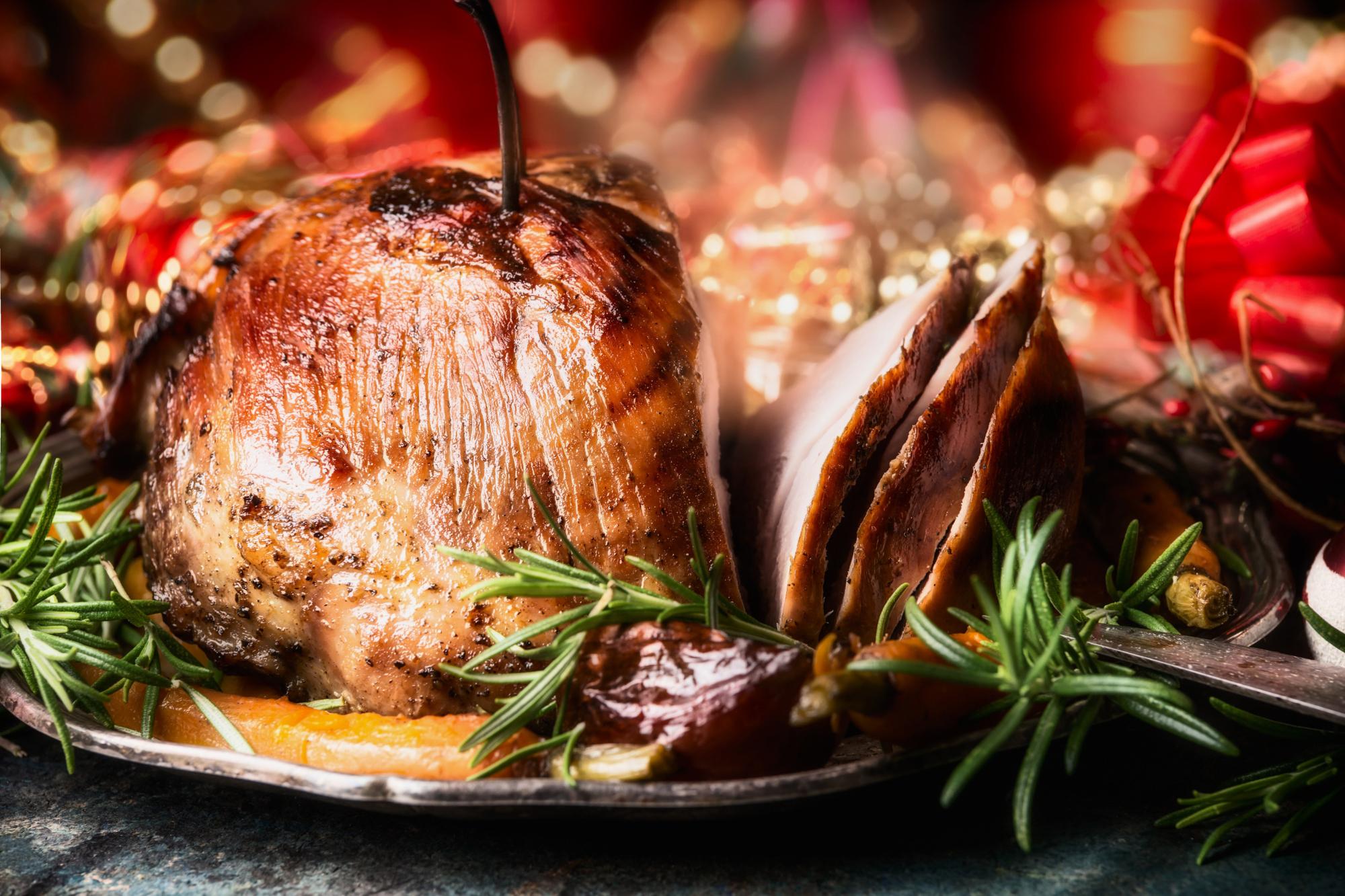 Christmas sliced roasted ham on dinning table with festive holiday decoration, side view,close up