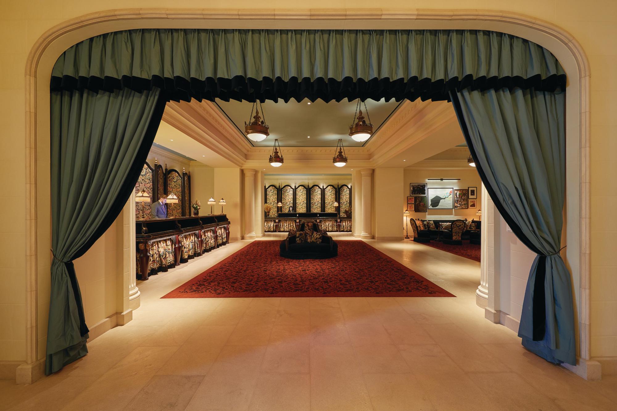 Reception of The Reserve at Park MGM with green curtains on the doorway, desks, chandeliers and a large red carpet.