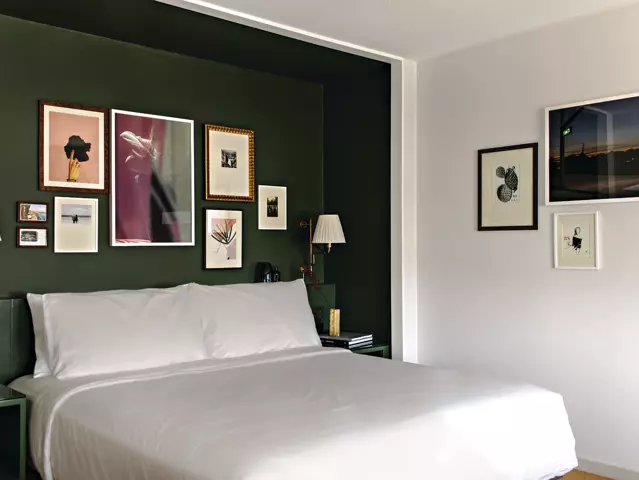 Park MGM hotel bedroom with a large bed dressed in crisp white linens and art frames on walls.