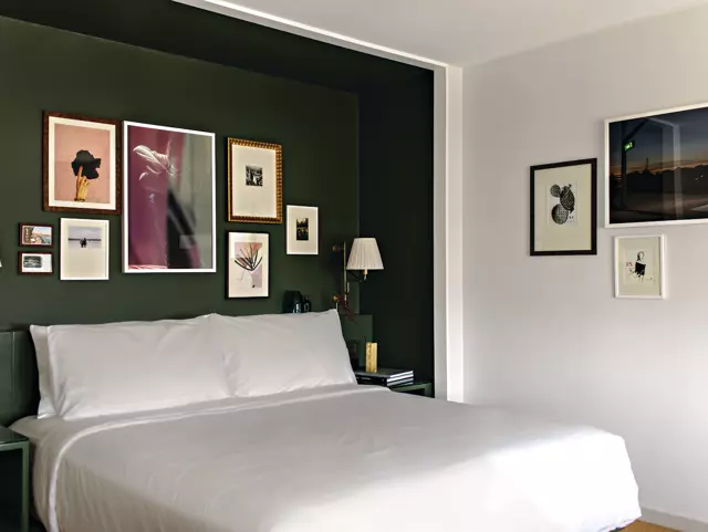 Green and white room at Park MGM with a queen-sized bed and art framed on the wall.