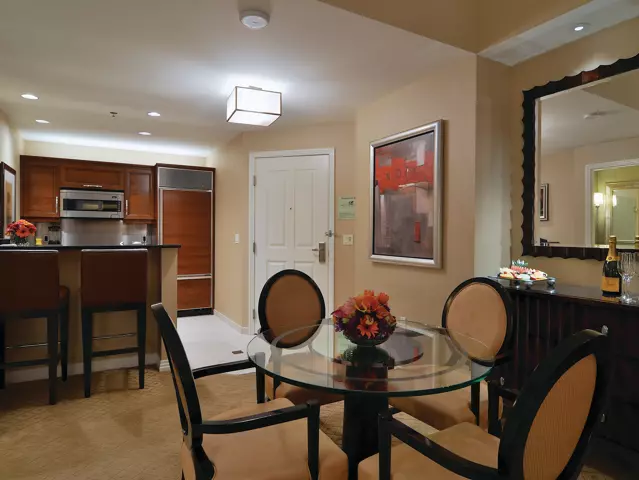 Kitchen in a room at The Signature at MGM Grand with 4-person dining table, refrigerator, oven and 2 table bar stools.