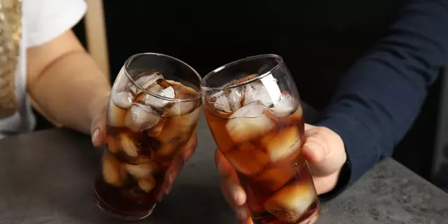 Friends with glasses of tasty refreshing cola at table, closeup view