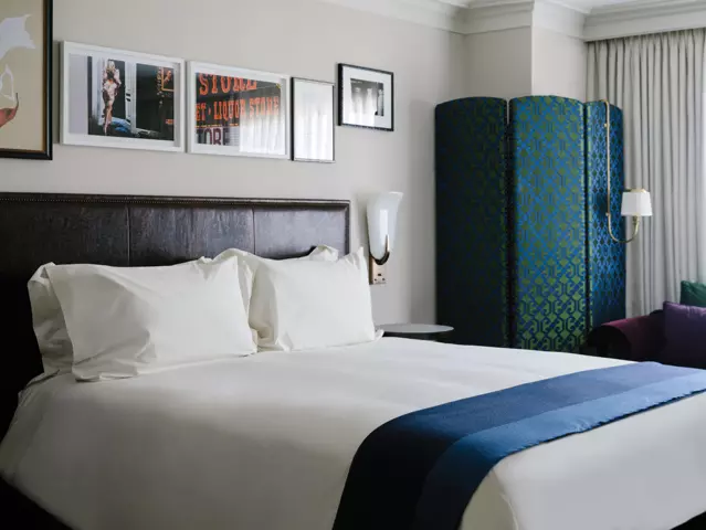 Park MGM hotel bedroom with a large bed dressed in crisp white linens and art frames on walls.