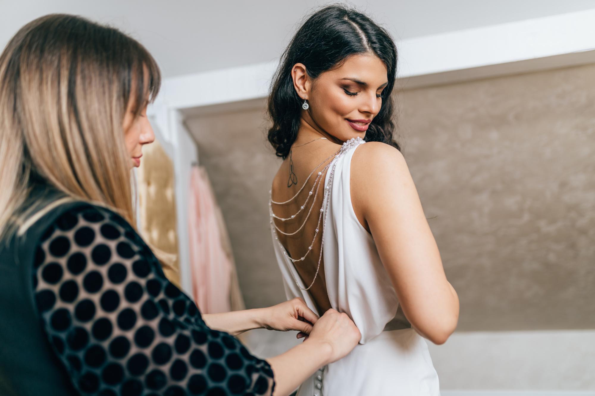 Beautiful young woman choosing a wedding dress in a modern wedding salon.