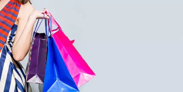 Young happy shopping woman with shopping bags isolated over grey background