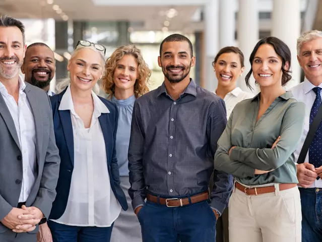 Portrait of successful group of business people at modern office looking at camera. Portrait of happy businessmen and satisfied businesswomen standing as a team. Multiethnic group of people smiling and looking at camera.