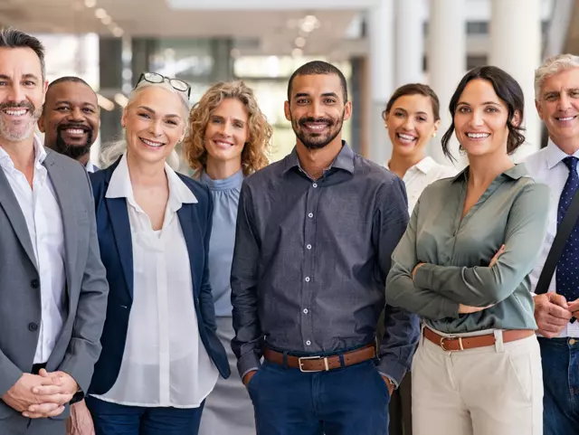 Portrait of successful group of business people at modern office looking at camera. Portrait of happy businessmen and satisfied businesswomen standing as a team. Multiethnic group of people smiling and looking at camera.