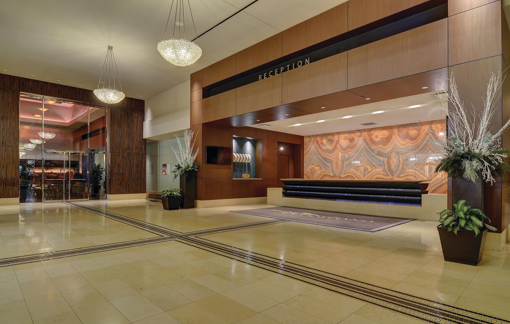 Reception of MGM Grand Detroit with a long reception desk, chandeliers and potted plants.