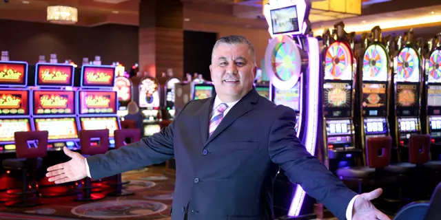MGM Grand Detroit casino host Yassir Yasso standing in front of the slot machines inside the casino with his hands out.