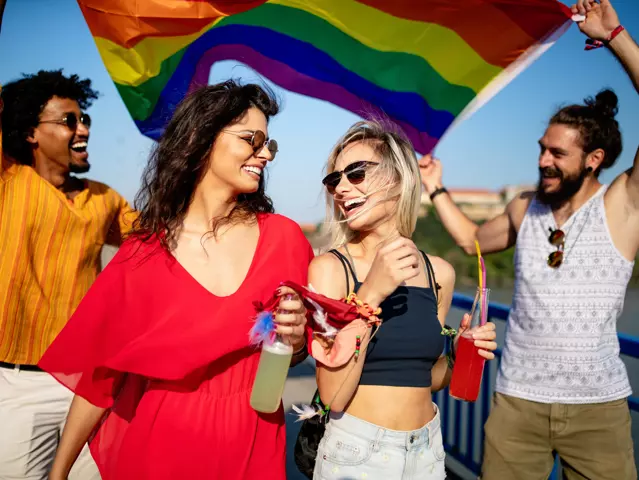 Pride homosexual, gay, lesbian community at a parade with hands raised and the LGBT flag