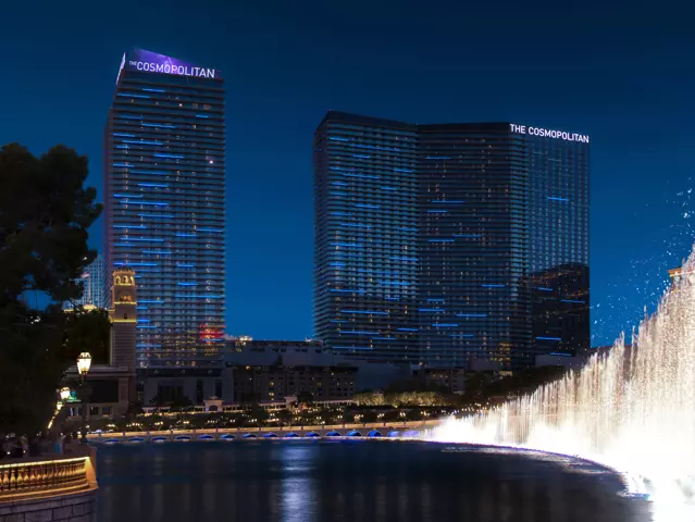 Exterior view of The Cosmopolitan hotel with a the Bellagio water fountains at night.