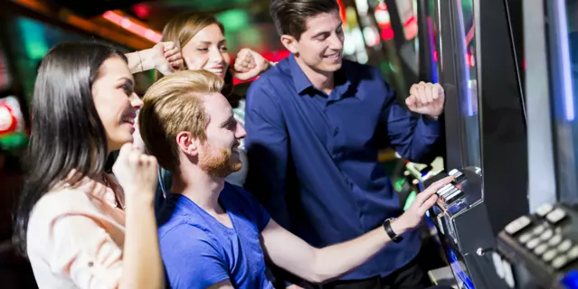 Young group of people gambling in a casino playing slot and various machines