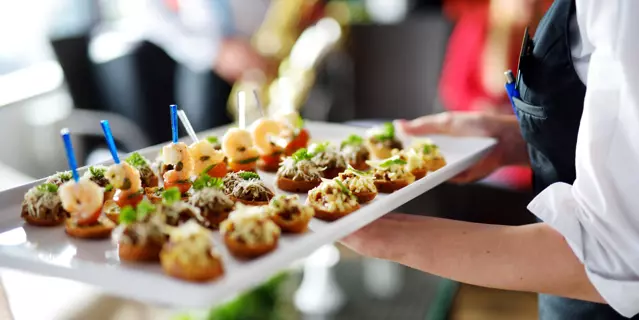 Waiter carrying plates with meat dish on some festive event, party or wedding reception