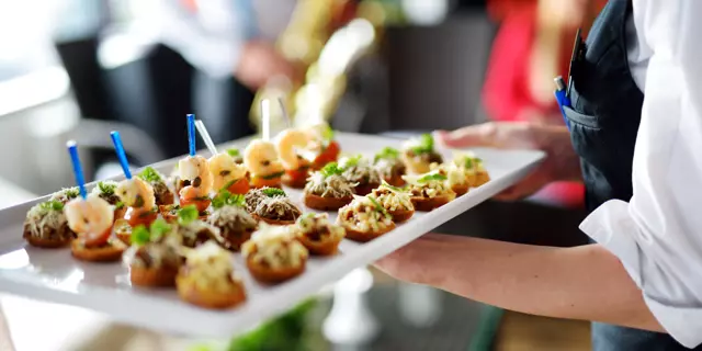 Waiter carrying plates with meat dish on some festive event, party or wedding reception