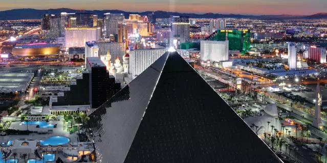 Exterior of Luxor shows a black glass pyramid-shaped building with a light beam shining up from the top.