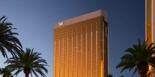 Exterior of W Las Vegas shows a glass building with 34 floors reflecting in the sunset surrounded by palm trees.