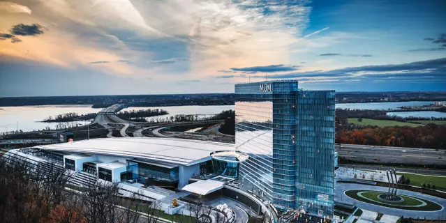 Exterior of the MGM National Harbor at night with 24 floors next to a large casino and close to a river.