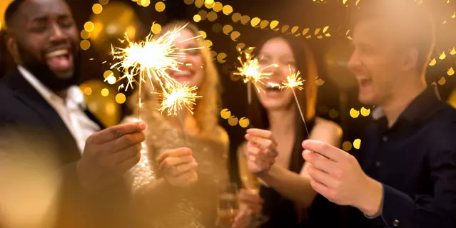 Overjoyed young people celebrating new year, holding bengal lights, having fun