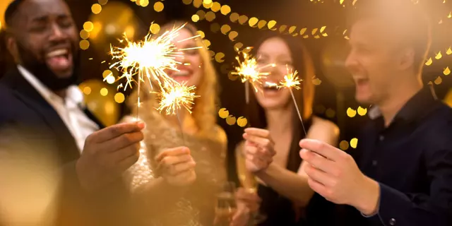 Overjoyed young people celebrating new year, holding bengal lights, having fun