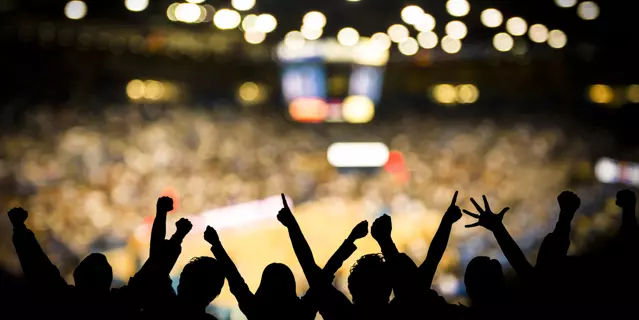 Fans excited at basketball game. Silhouetted fans raising arms in celebration at a basketball game.