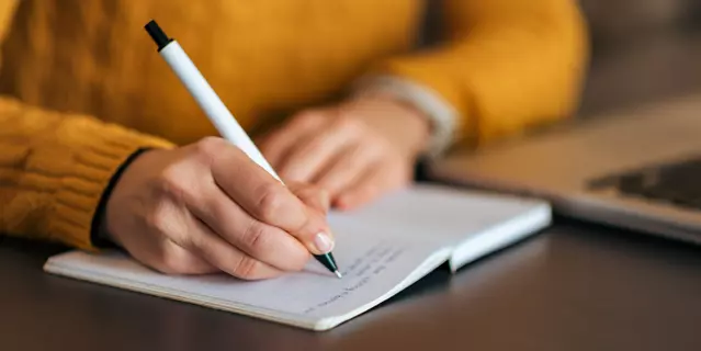 Writing in notebook. Close-up.