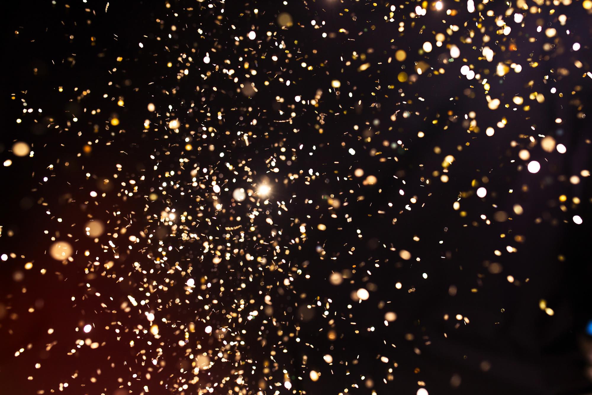 Photo of golden glitter on a black background. Golden explosion of confetti. Holiday background