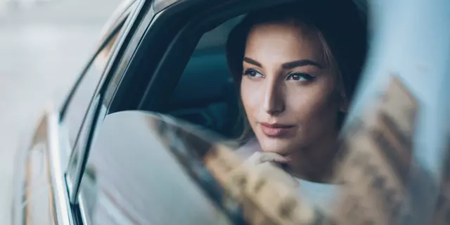 Young woman on the back seat of a car looking out of the window.