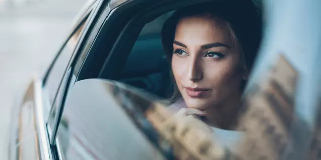 Young woman on the back seat of a car looking out of the window.