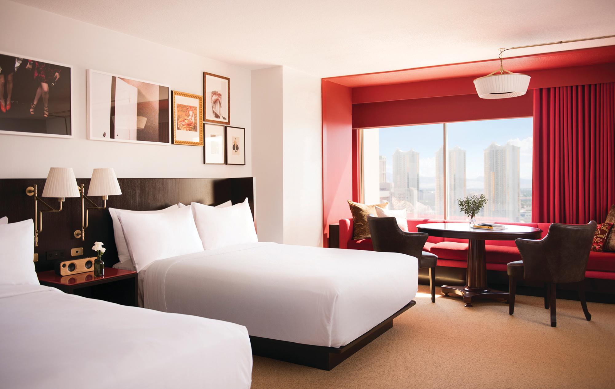 Red and white room at Park MGM with 2 queen-sized beds, a round table and Vegas strip view.